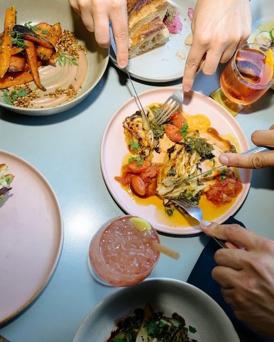 Small plates and a glass of wine shared across a table at Buddy